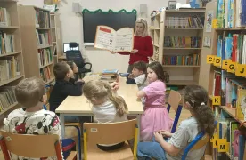 Dzieci słuchają czytania w bibliotece.