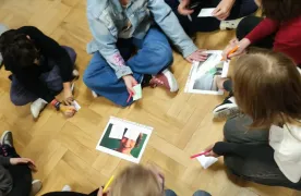 Uczniowie rozwiązujący zadanie siedząc na korytarzu szkolnym