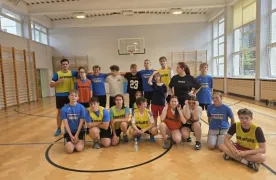Uczniowie uczestniczący w międzyklasowym turnieju unihokeja pozują do wspólnego zdjęcia na sali gimnastycznej.