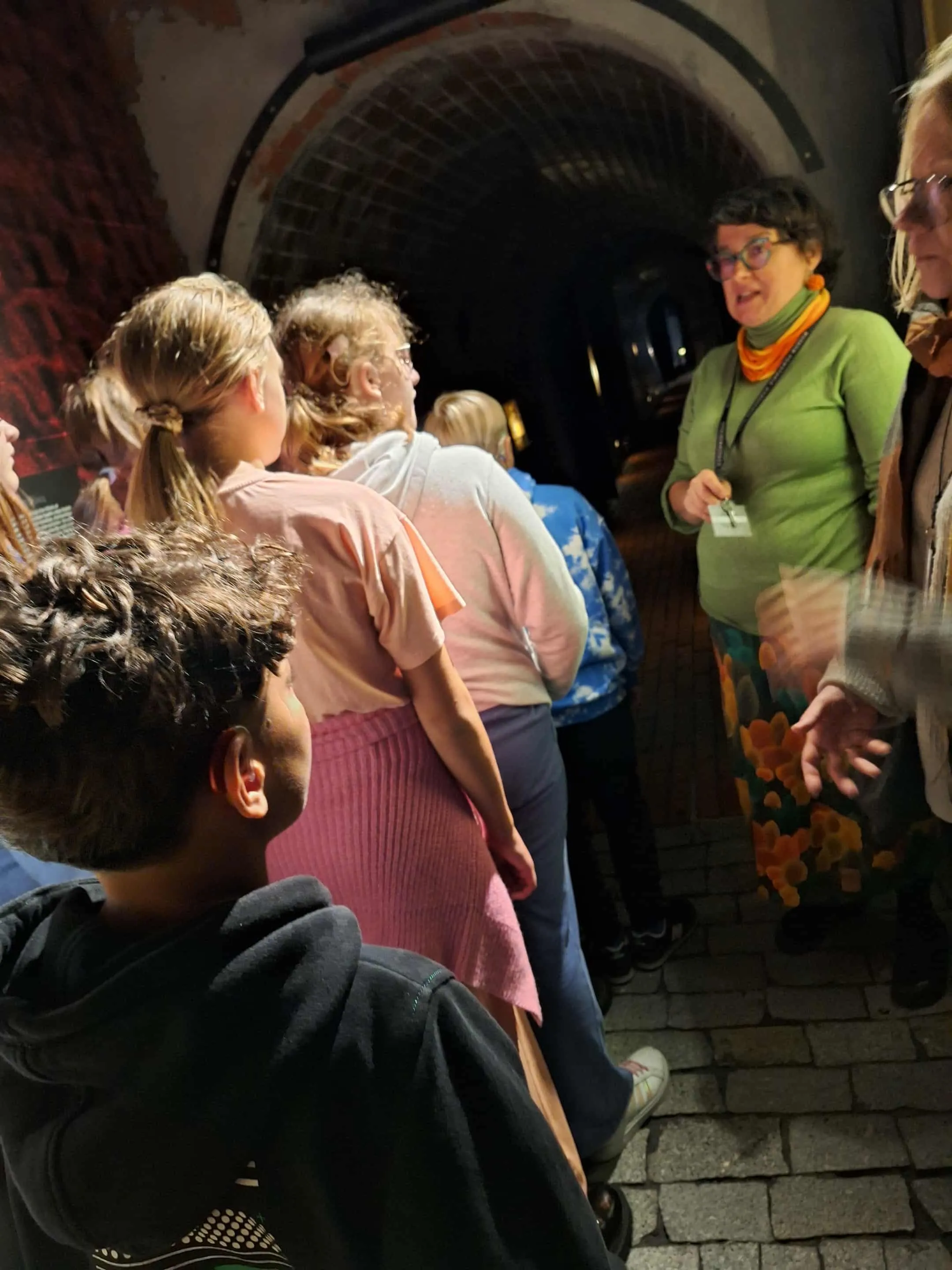 Uczniowie w podziemiach słuchający przewodnika