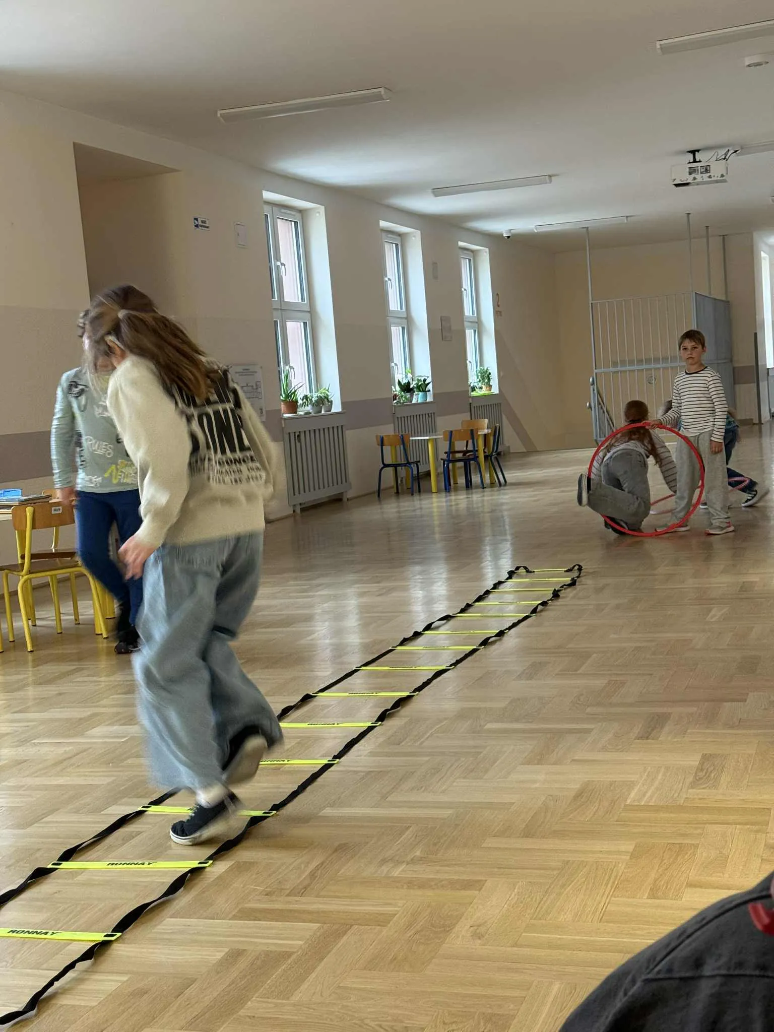 Uczniowie ćwiczący na drabince koordynacyjnej