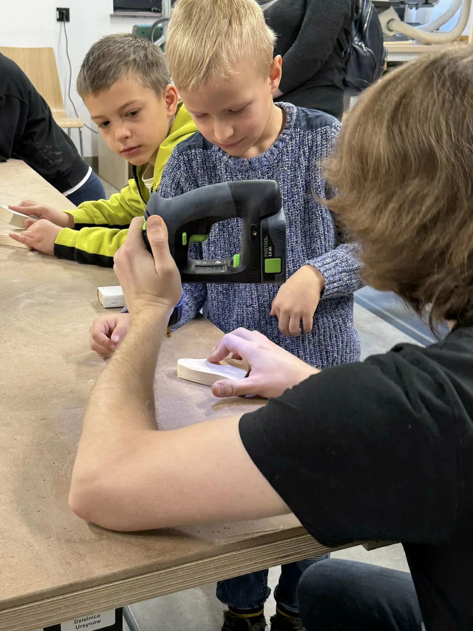 Dziecko z pomocą pana wycinające pingwina z drewna