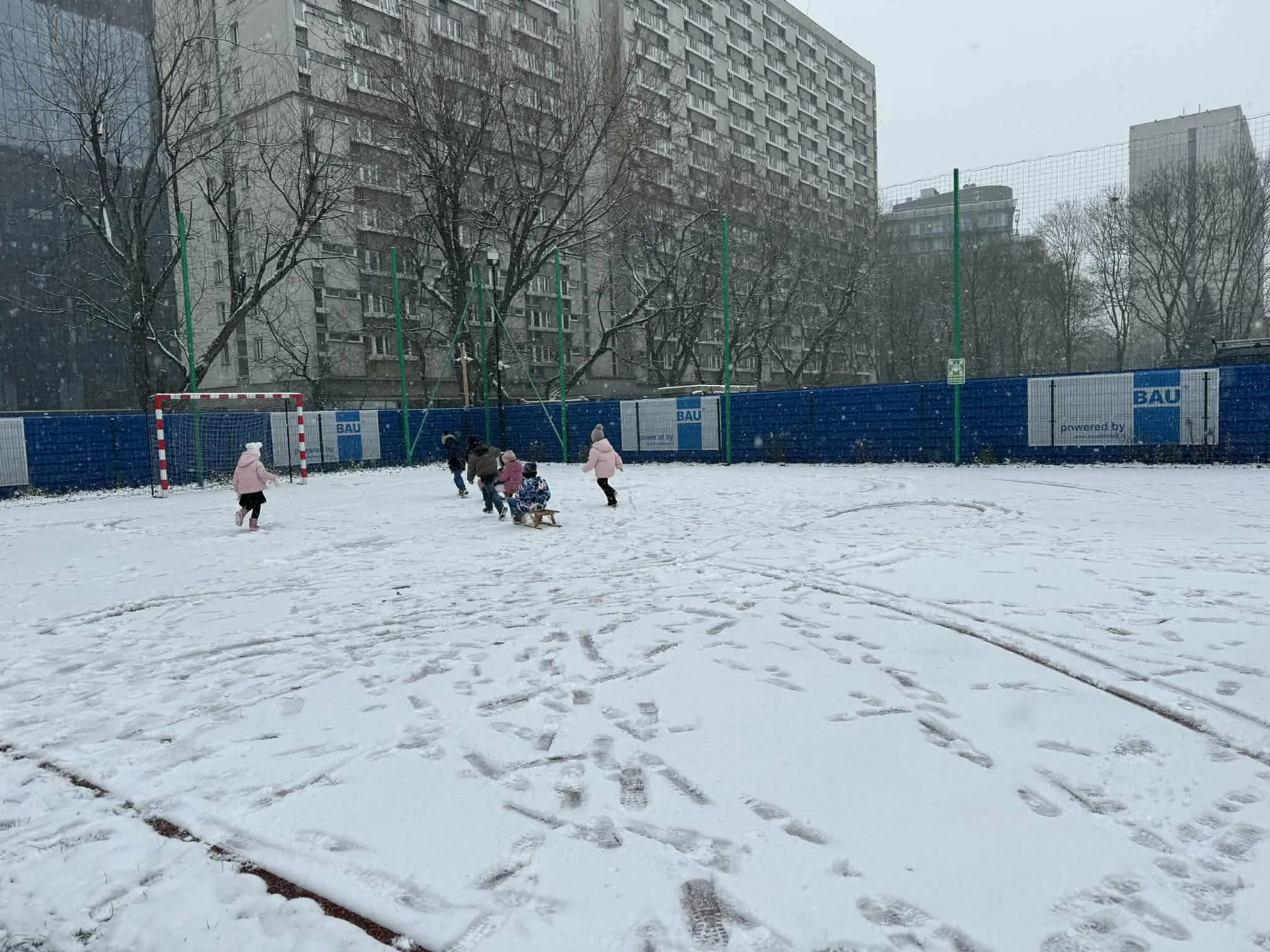 Przedszkolaki jeżdżące na sankach 
