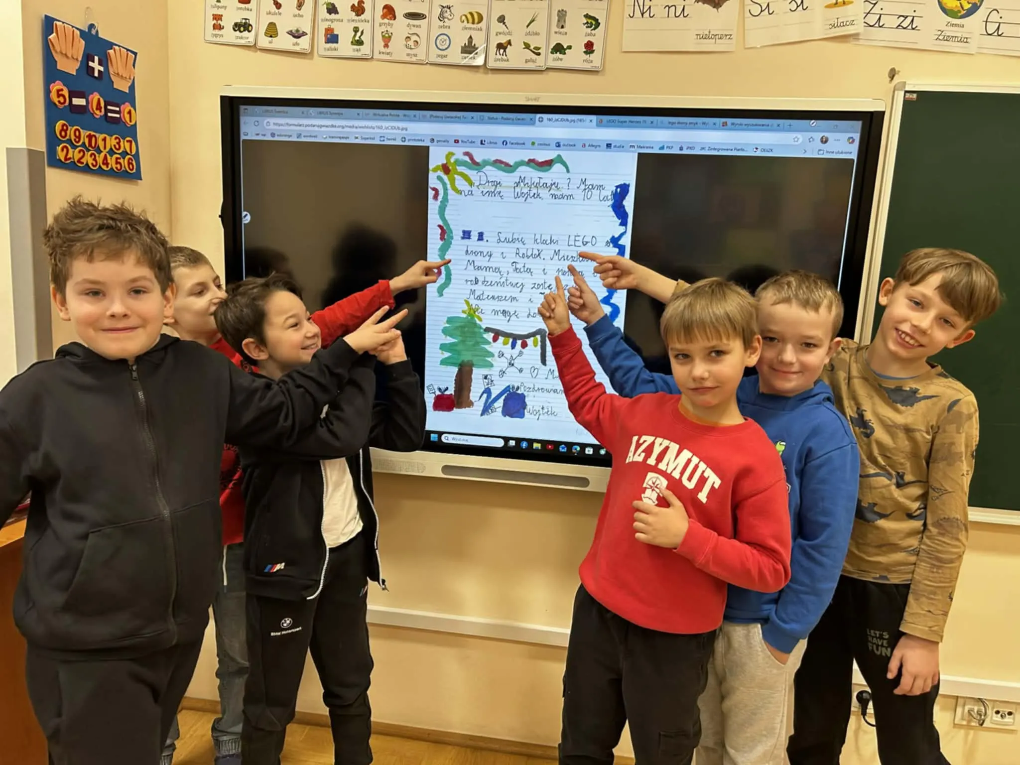 Uczniowie przy tablicy pokazujący wybrany list wybranego dziecko do Mikołaja