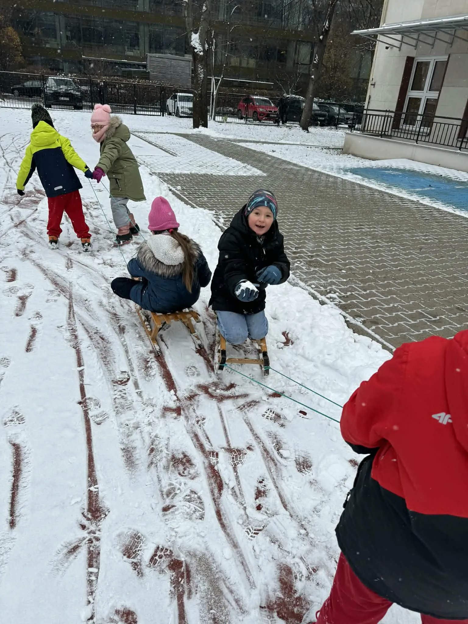 Przedszkolaki jeżdżące na sankach 