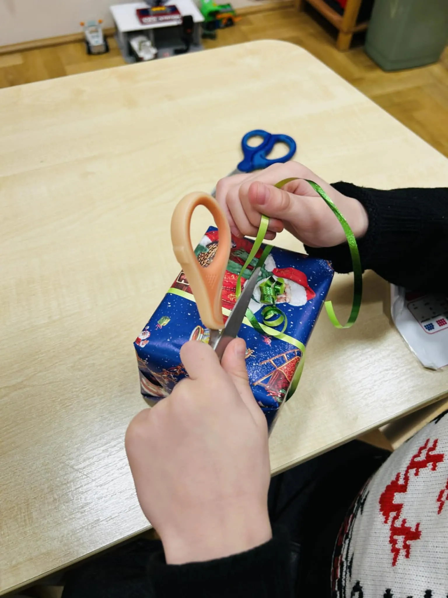 Dziecko przycina wstążkę nożyczkami.