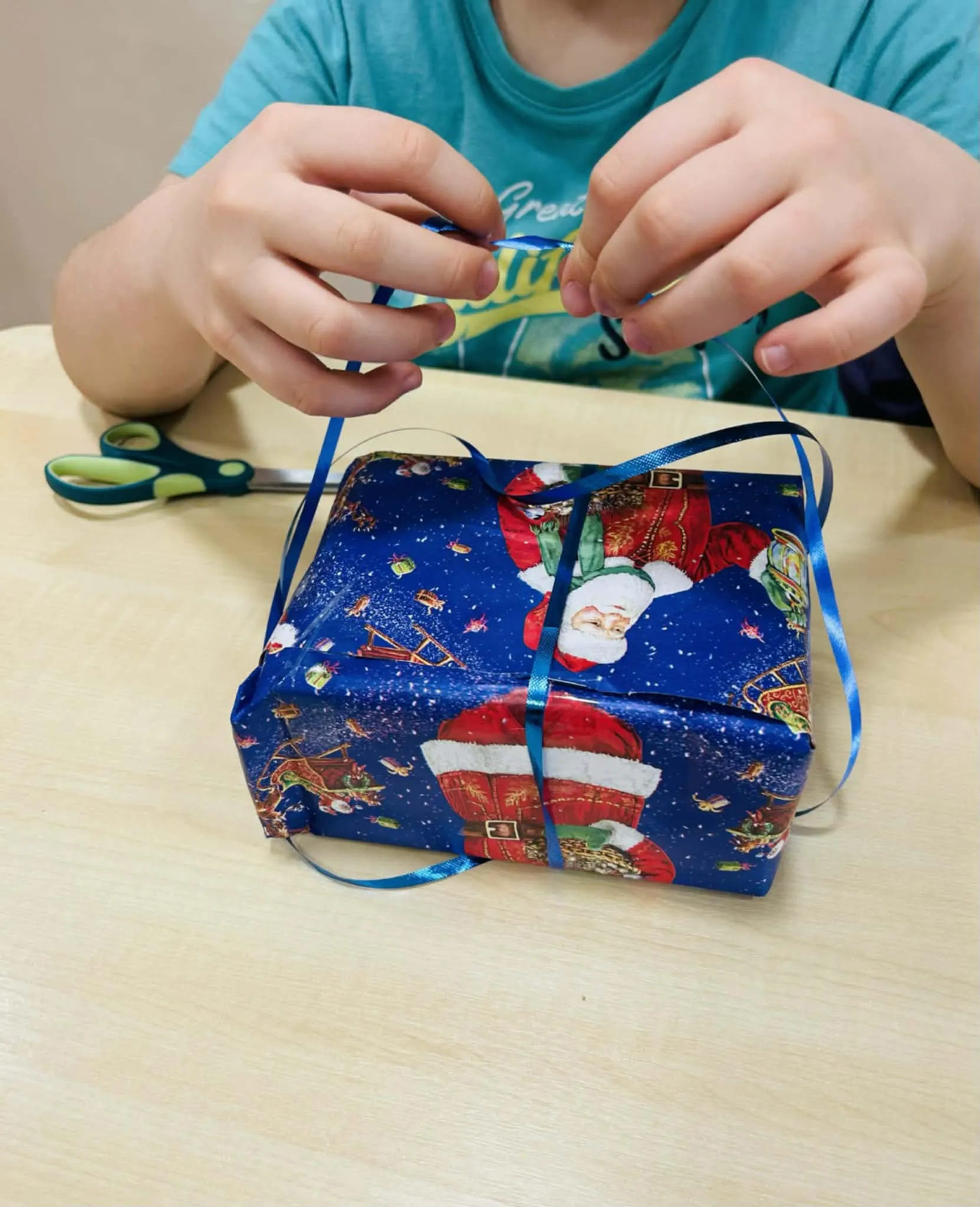 Dziecko wiąże wstążkę na prezencie.