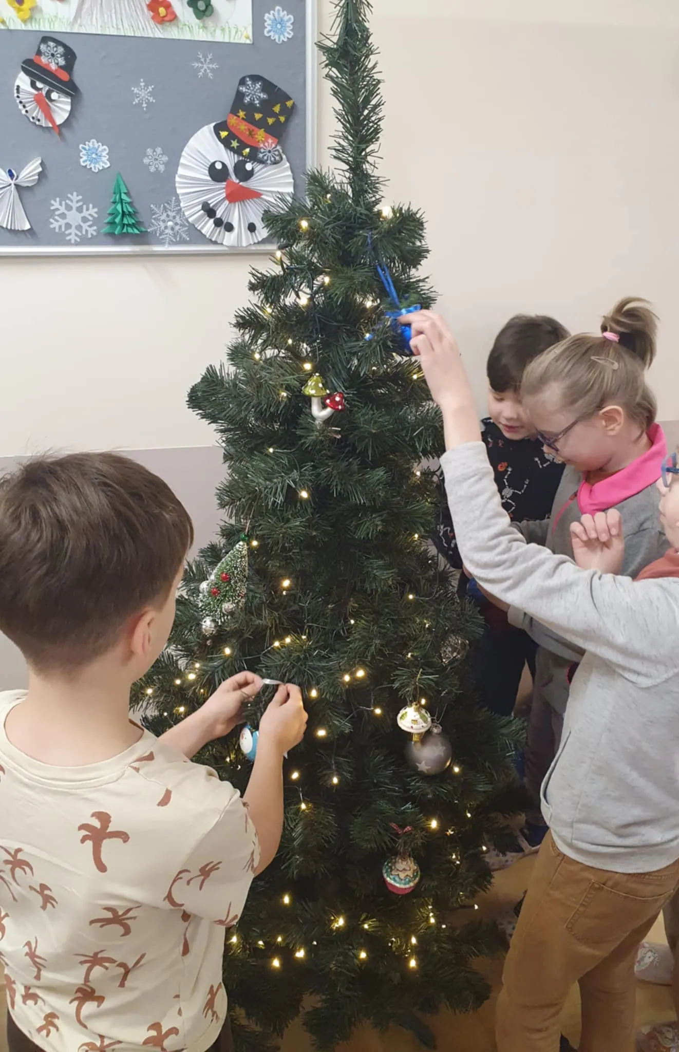 Uczniowie ubierający choinkę