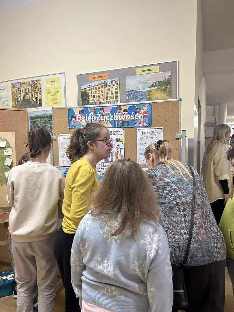 Uczniowie odrywający kartki z tablicy życzliwośći 