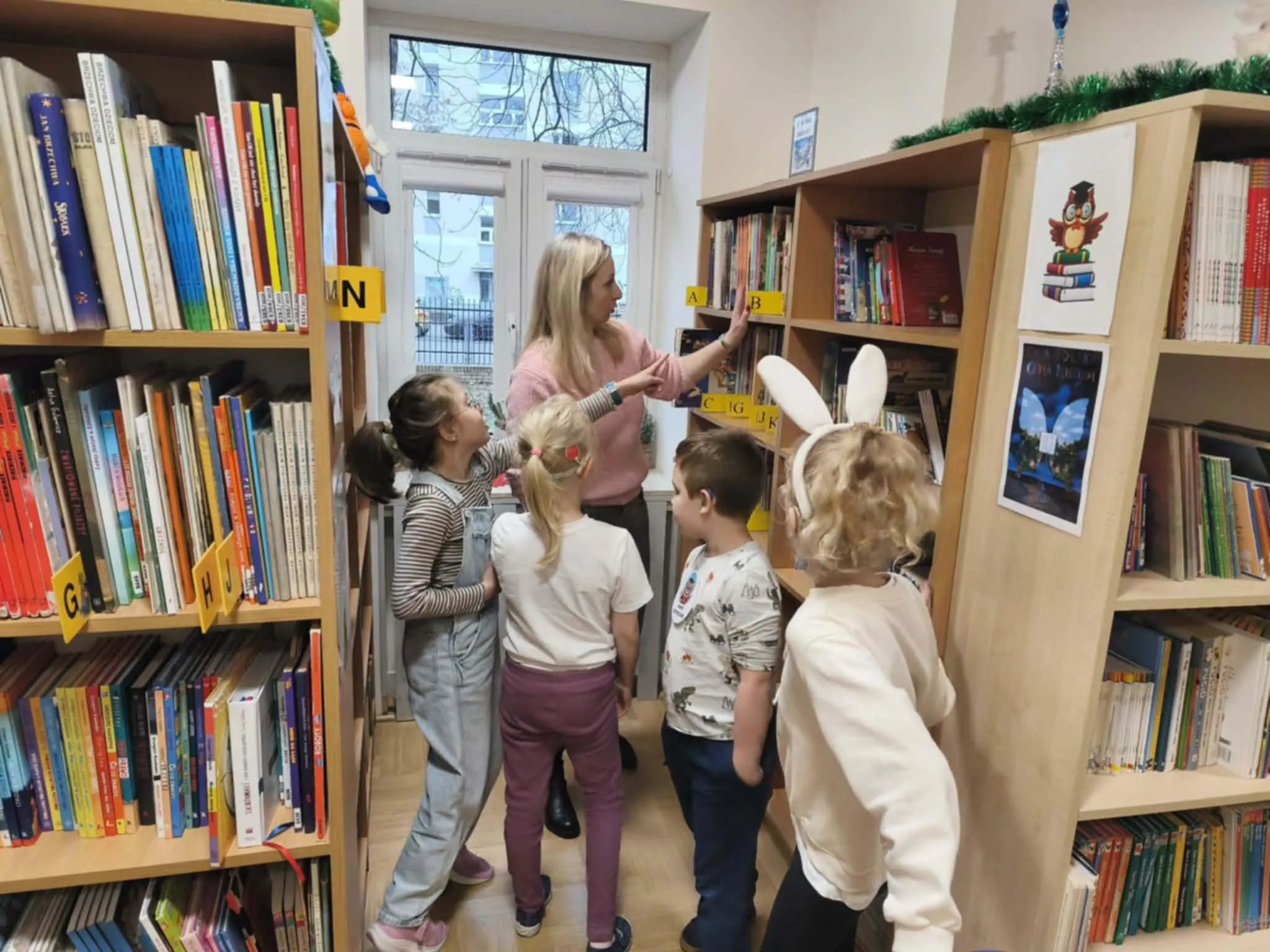 Dzieci stoją przy regałach z książkami.