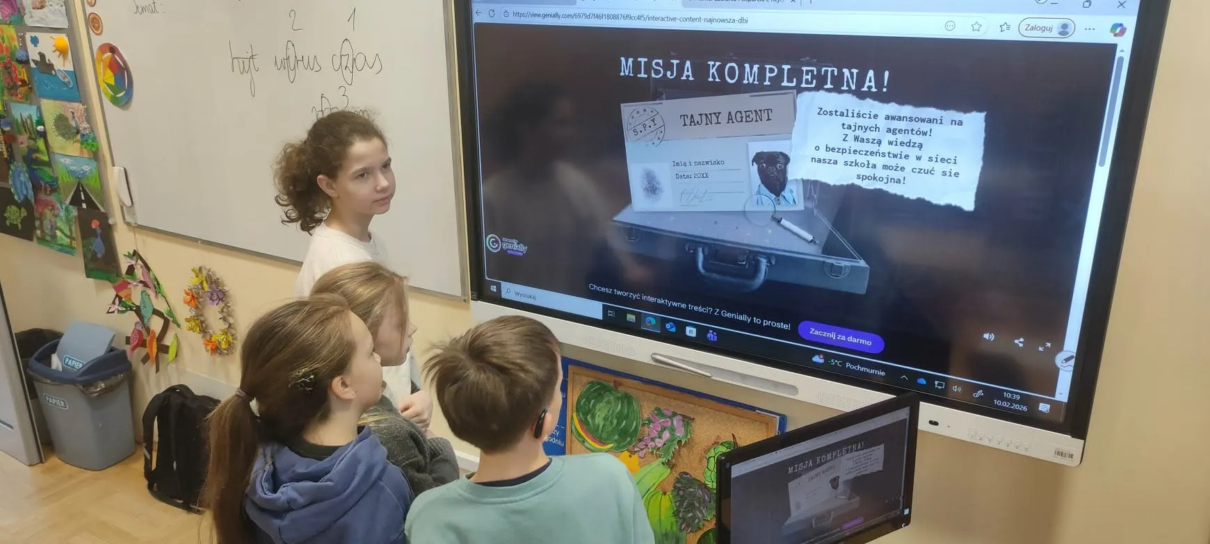 uczniowie stoją przed tablicą interaktywną i rozwiązują zadania