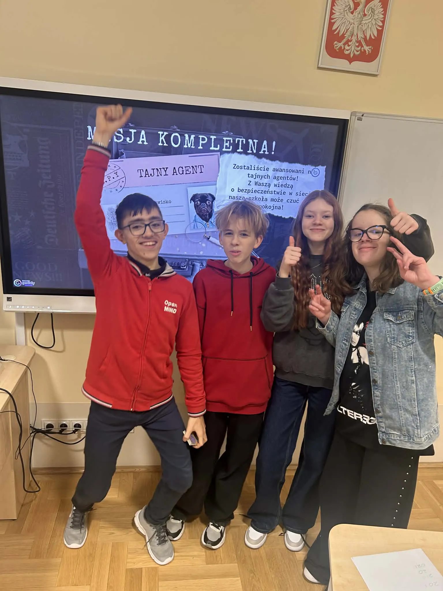 Uczennica pozują do zdjęcia grupowego przed tablicą interaktywną