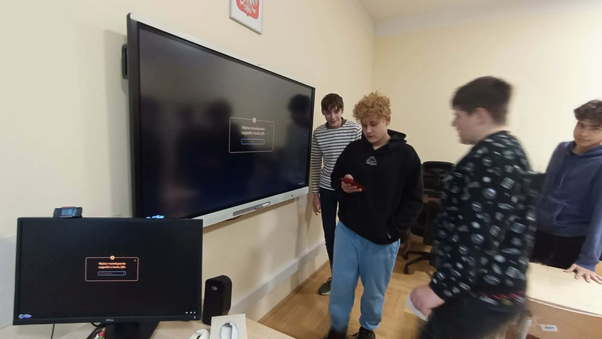 uczniowie stoją przed tablicą interaktywną i rozwiązują zadania