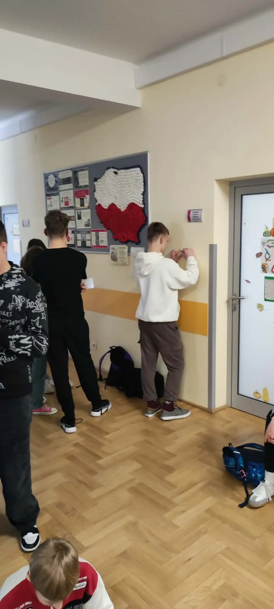 Uczeń rozwiązuję zadanie na kartce opierając się o ścianę