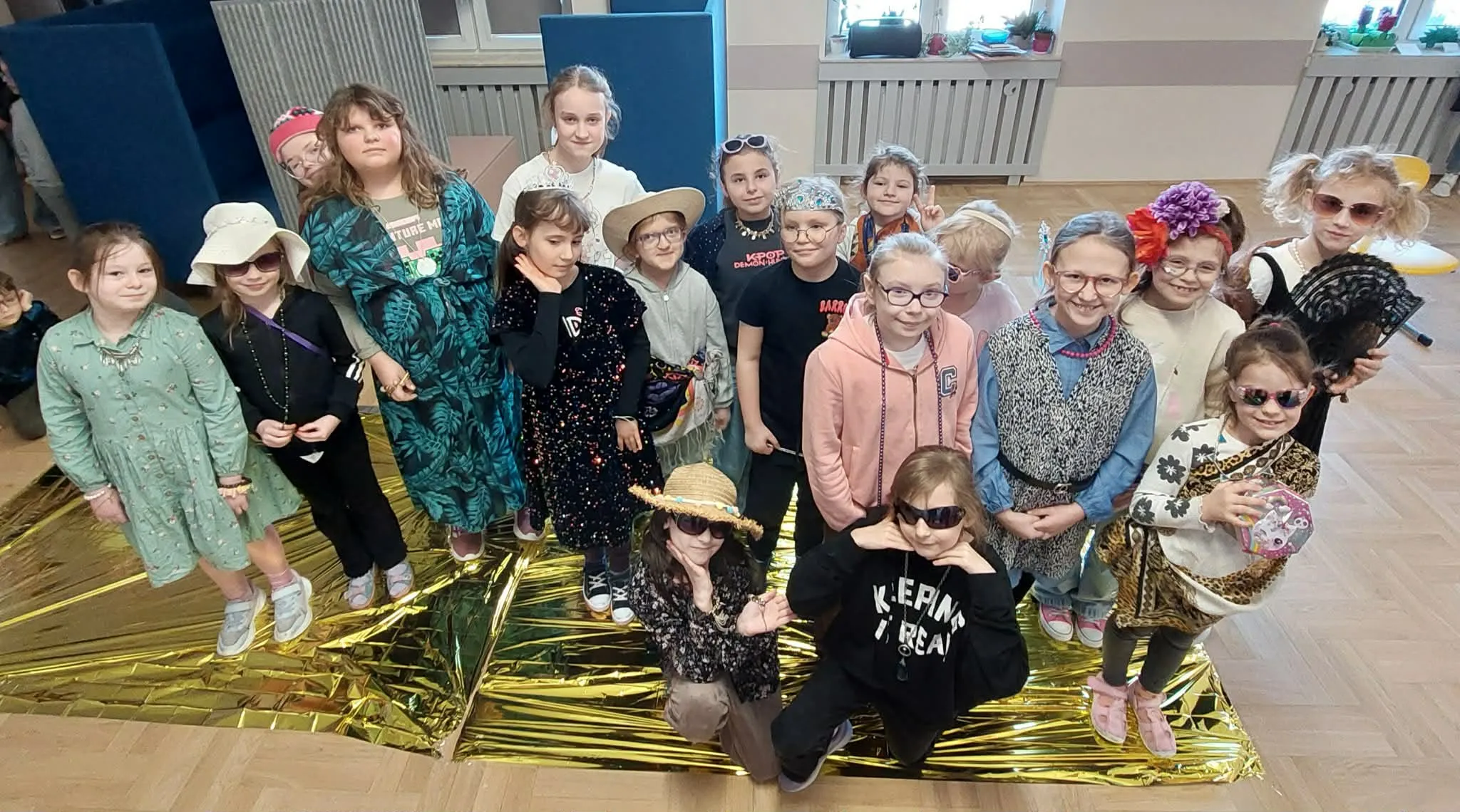 Grupa dzieci przebranych w różne dodatki i stroje stoi razem podczas szkolnych obchodów Dnia Kobiet.