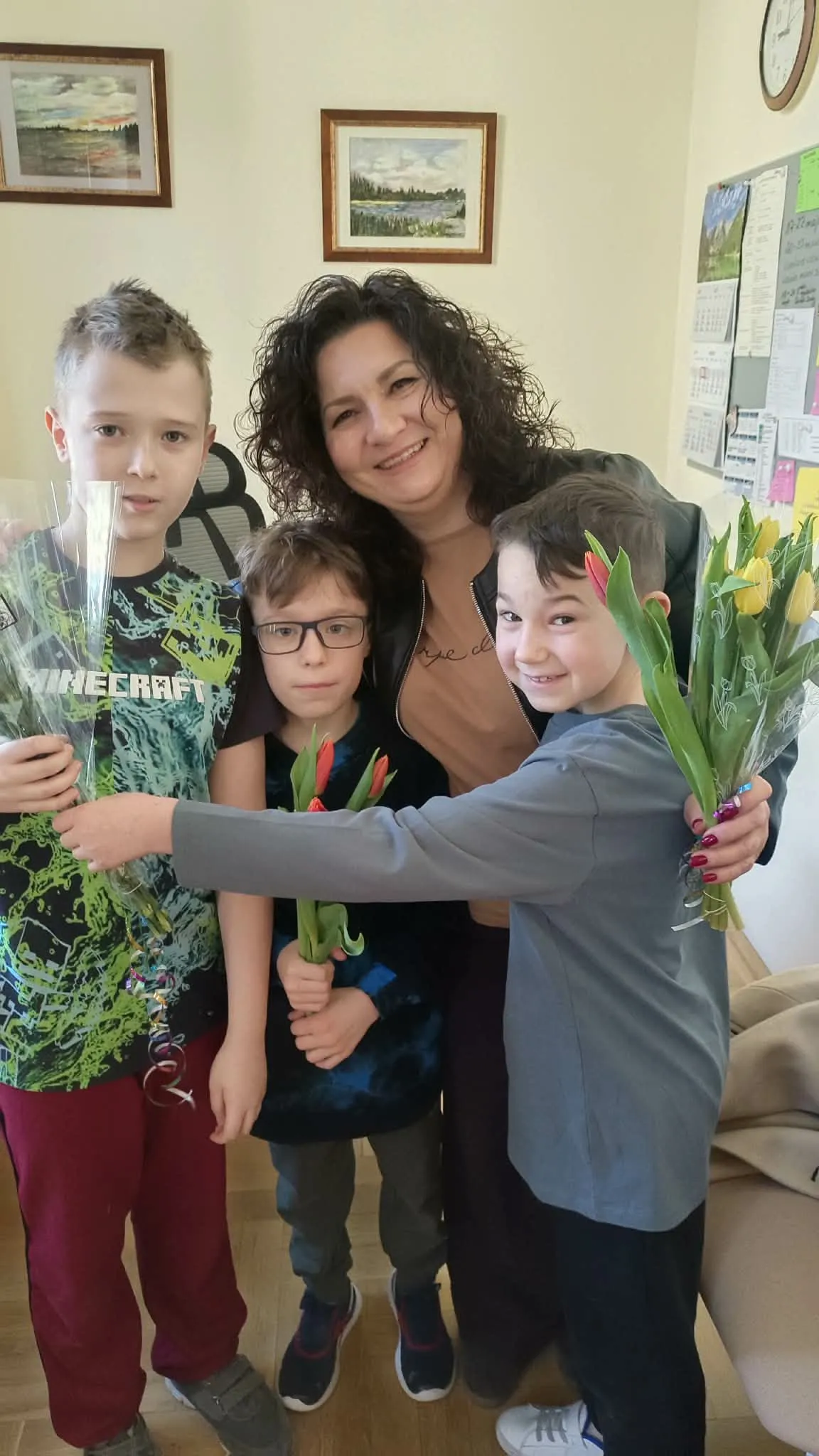 Chłopcy wręczają nauczycielce tulipany z okazji Dnia Kobiet.