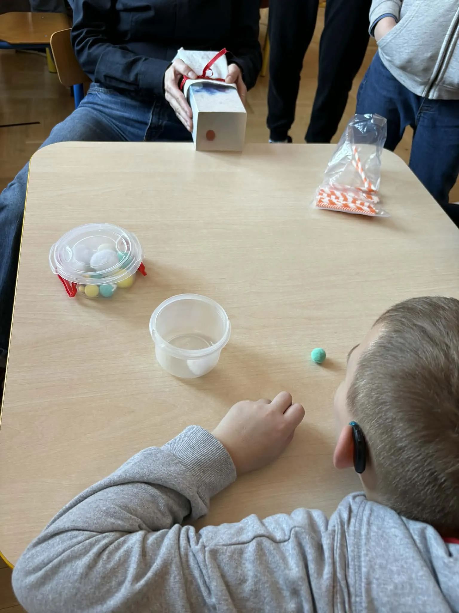 Dziecko wykonuje ćwiczenia oddechowe przy użyciu małych przedmiotów podczas zajęć