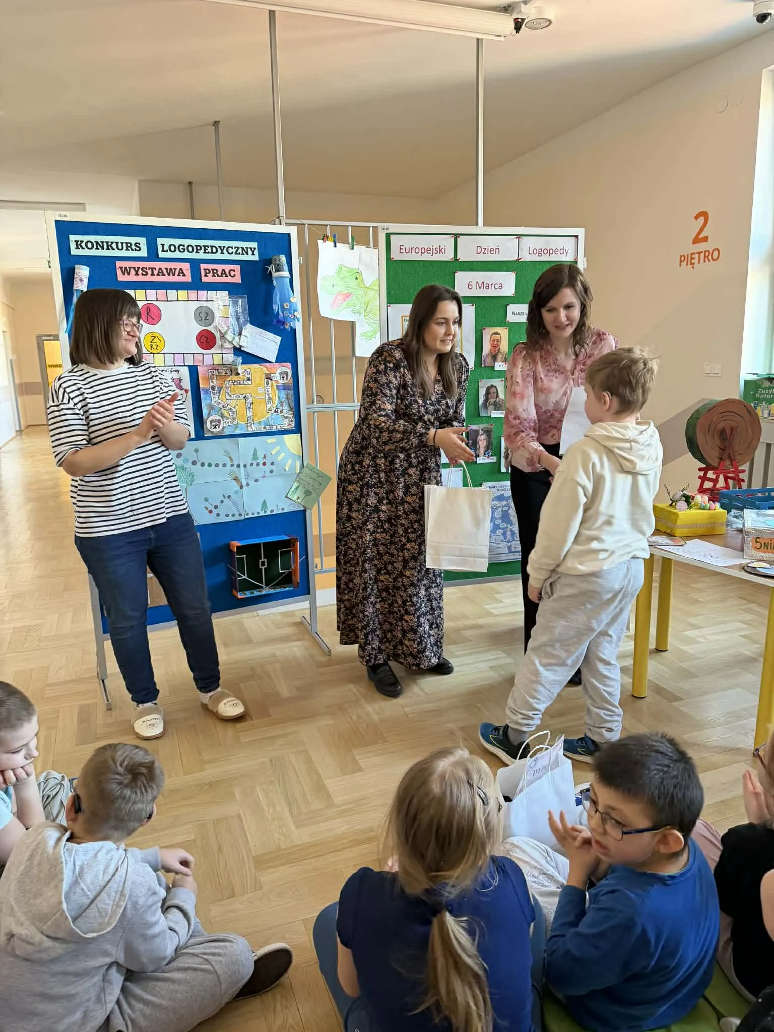 Nauczycielki wręczają nagrody uczniowi podczas szkolnego wydarzenia logopedycznego