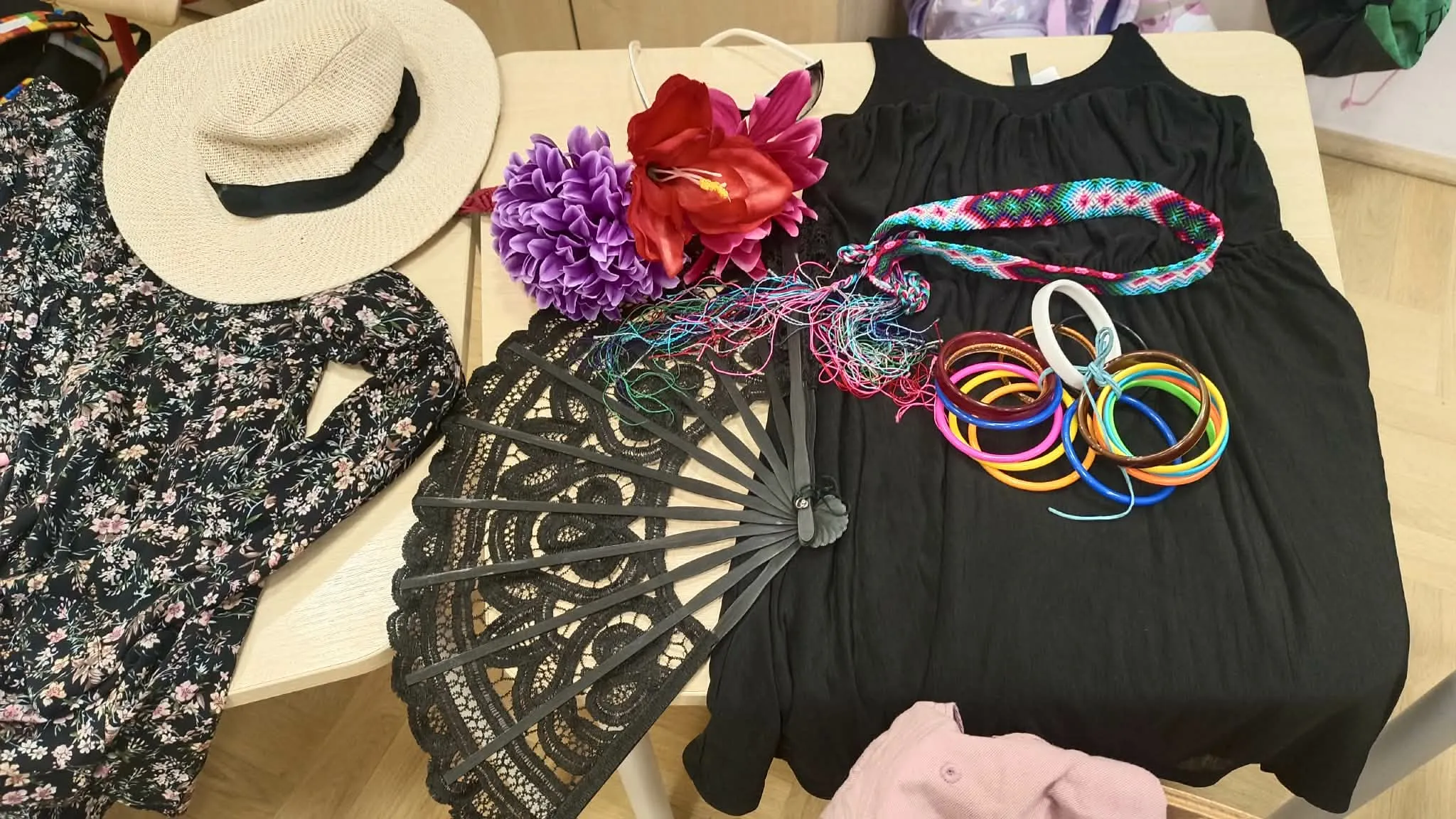 Kapelusz, wachlarz, biżuteria i sukienka przygotowane jako rekwizyty do szkolnej zabawy z okazji Dnia Kobiet.