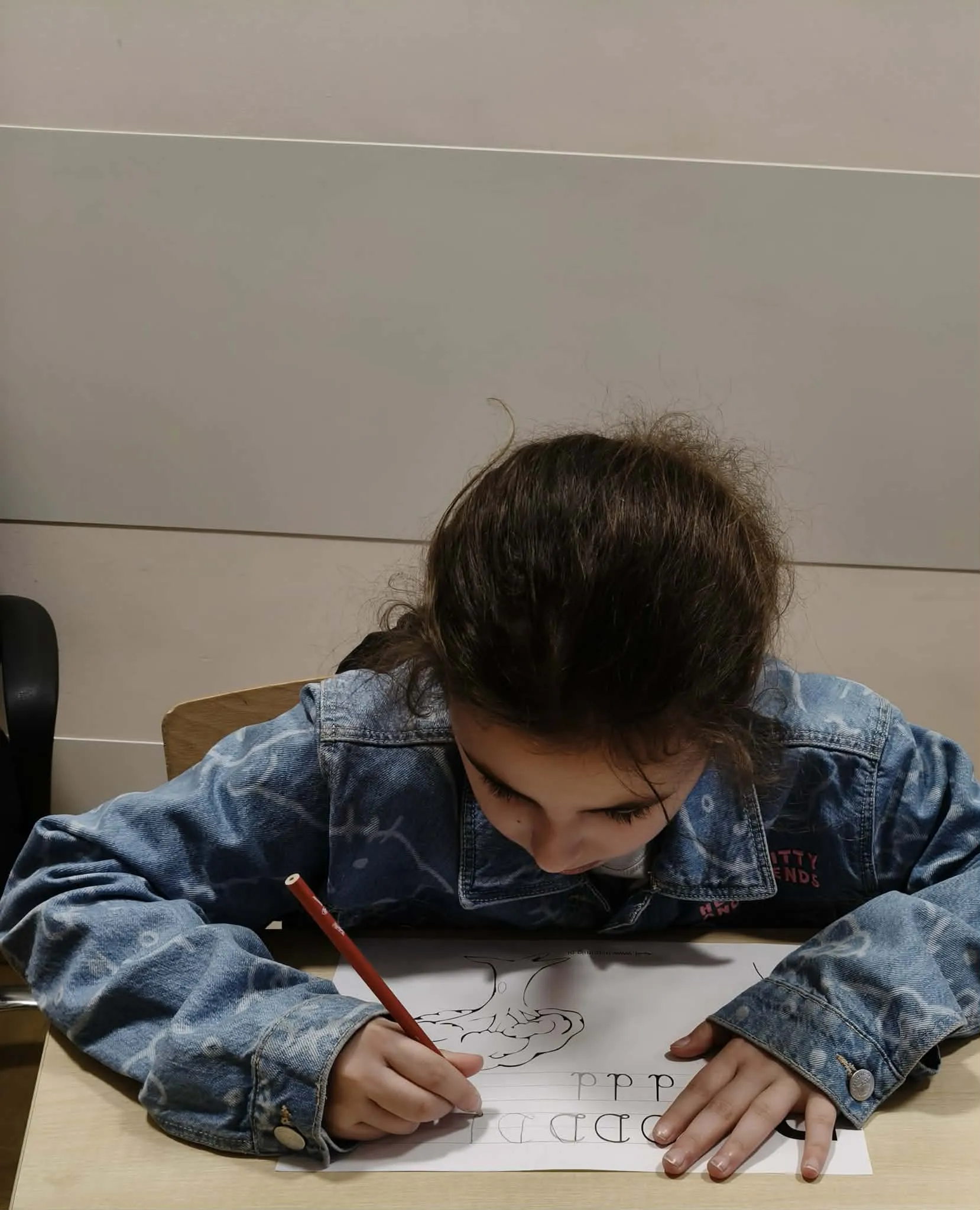 Dziewczynka pisze ołówkiem na kartce podczas nauki pisania