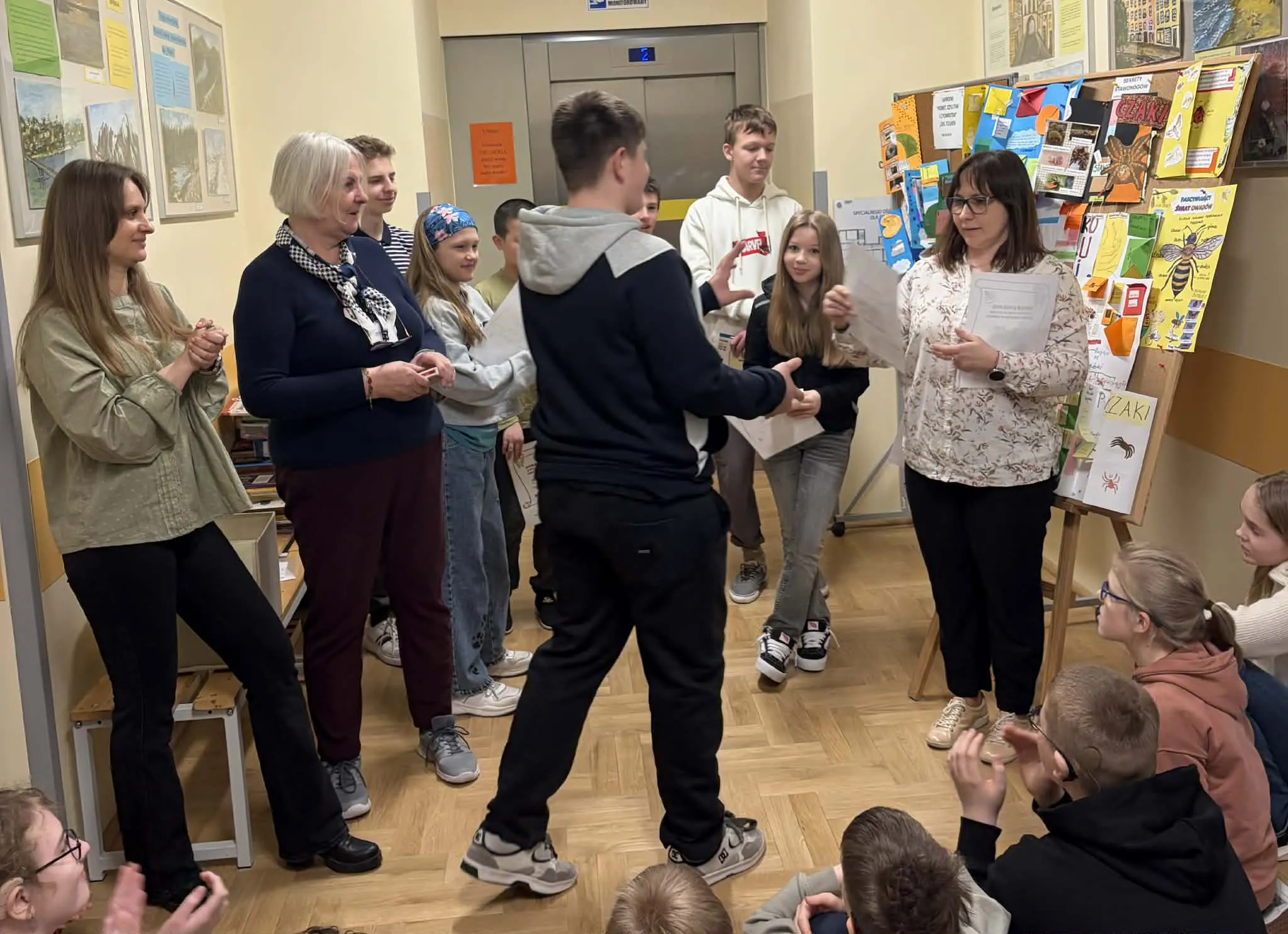 Uczeń odbiera dyplom podczas szkolnego podsumowania projektu