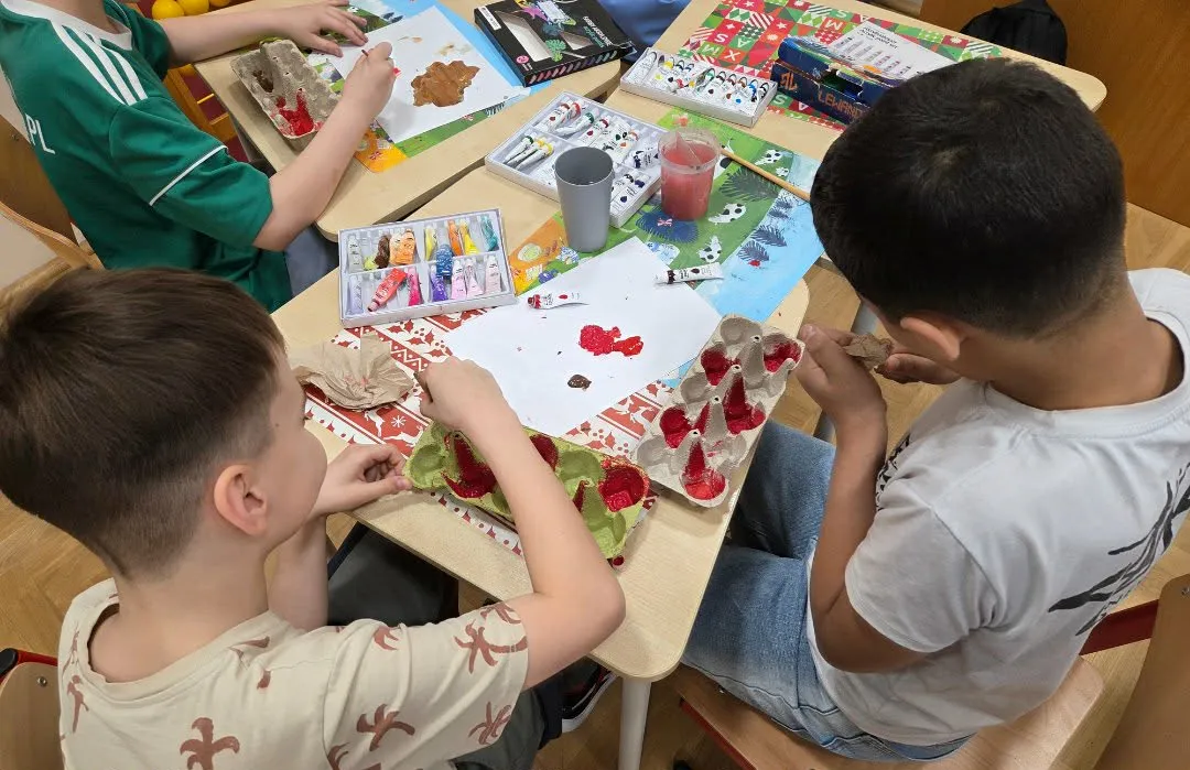 Uczniowie malują wytłoczki po jajkach i tworzą prace plastyczne przy stolikach