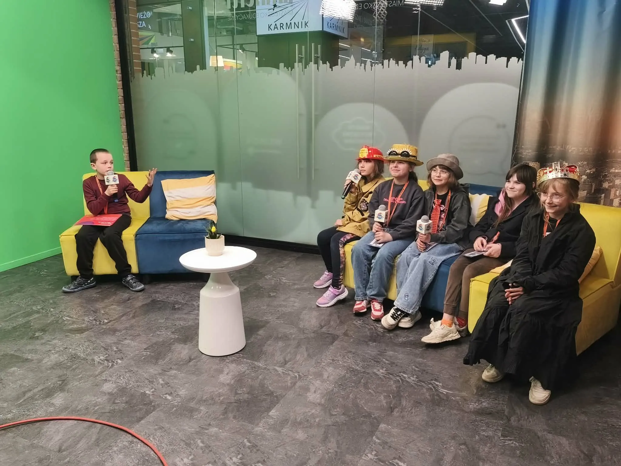 Uczniowie uczestniczą w nagraniu programu w studiu telewizyjnym z mikrofonami w dłoniach