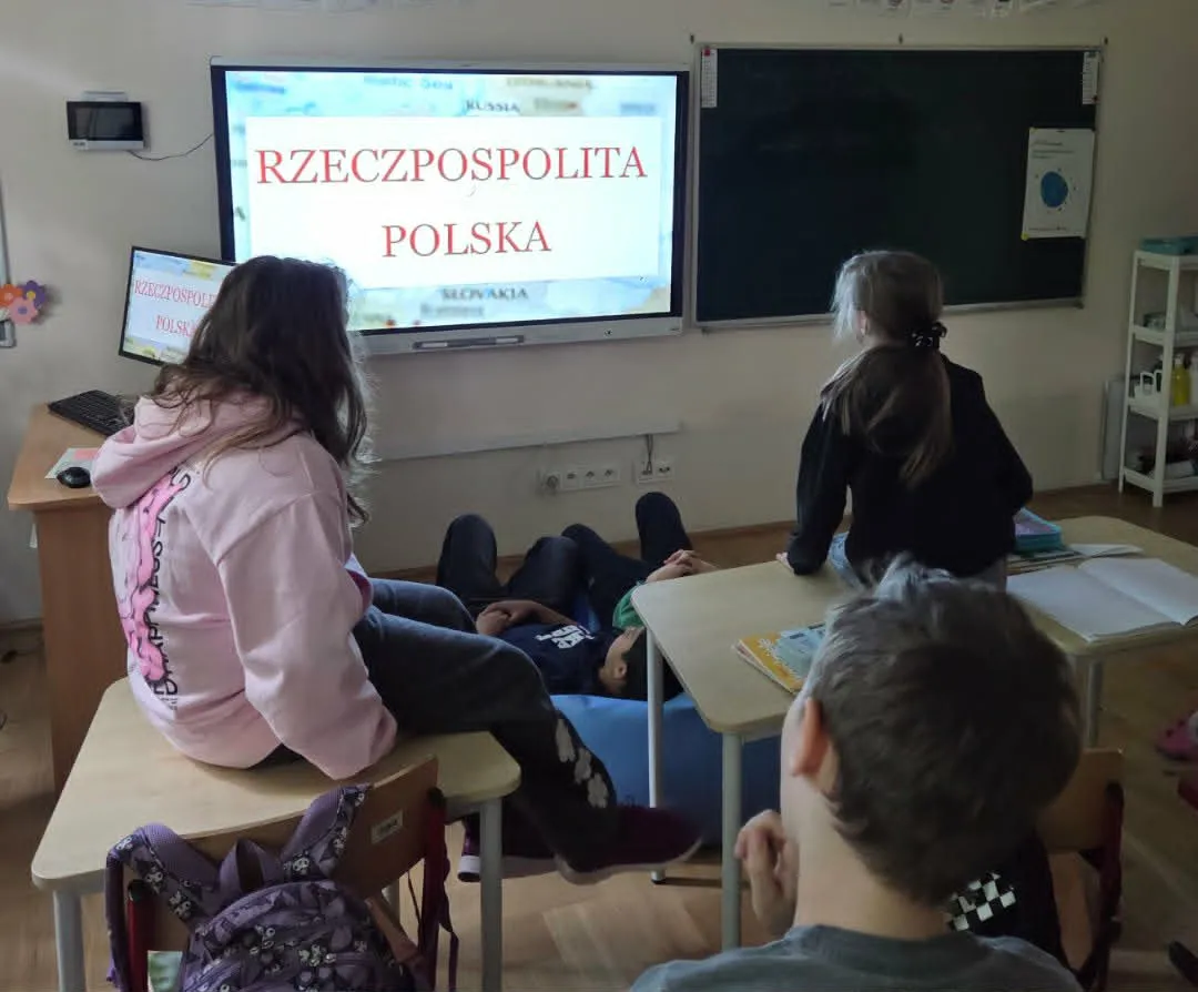 Uczniowie w klasie oglądają prezentację na tablicy interaktywnej z napisem Rzeczpospolita Polska podczas zajęć patriotycznych.