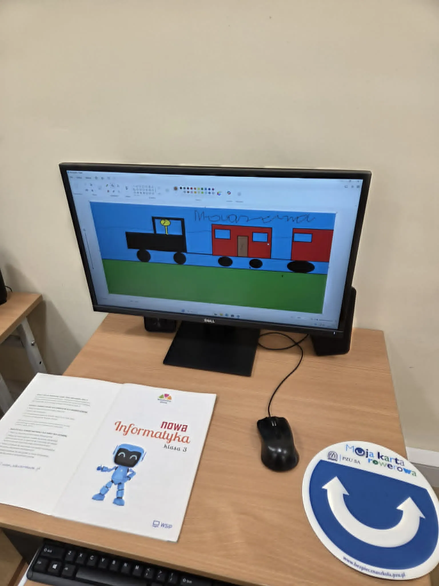 Na monitorze komputera widoczny jest wykonany przez ucznia rysunek lokomotywy i wagonów w programie Paint.