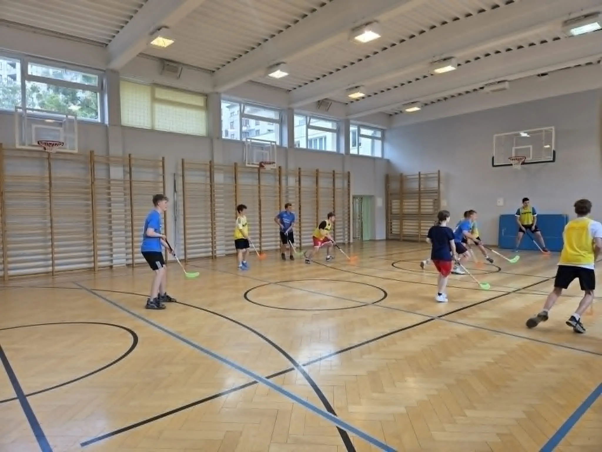 Uczestnicy turnieju unihokeja rywalizują na boisku, prezentując zaangażowanie i sportowego ducha walki.
