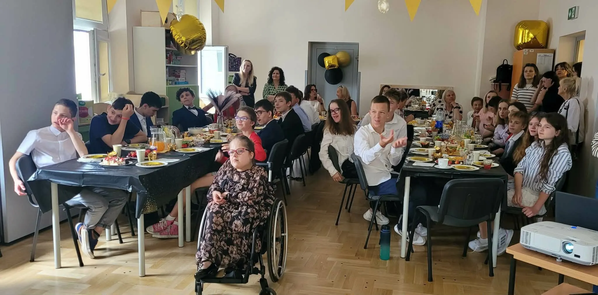 bal ósmoklasisty - uczniowie z nauczycielami siedzą za stołami