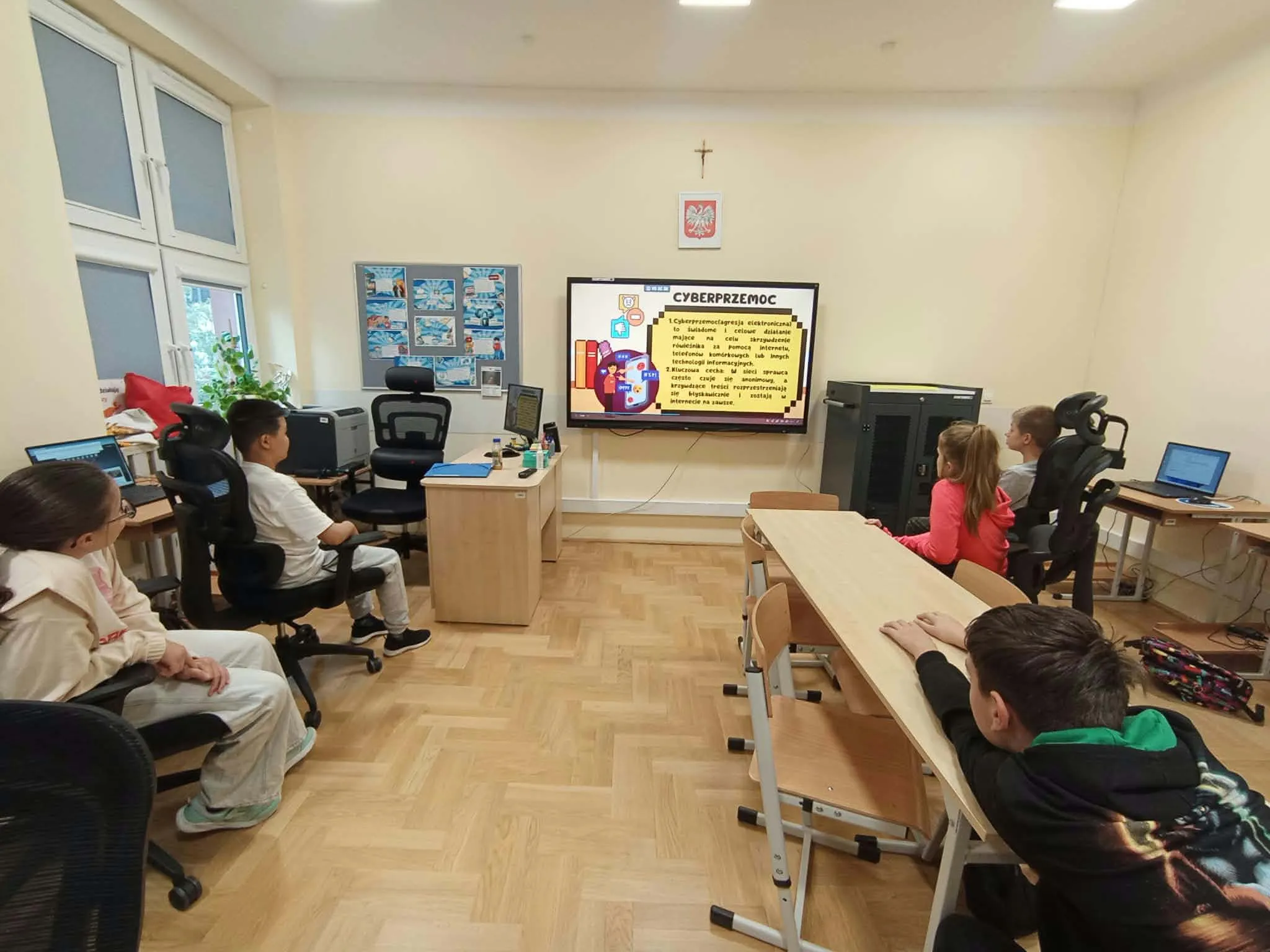 Uczniowie podczas zajęć z informatyki oglądają prezentację dotyczącą cyberprzemocy oraz zasad bezpiecznego zachowania w internecie.