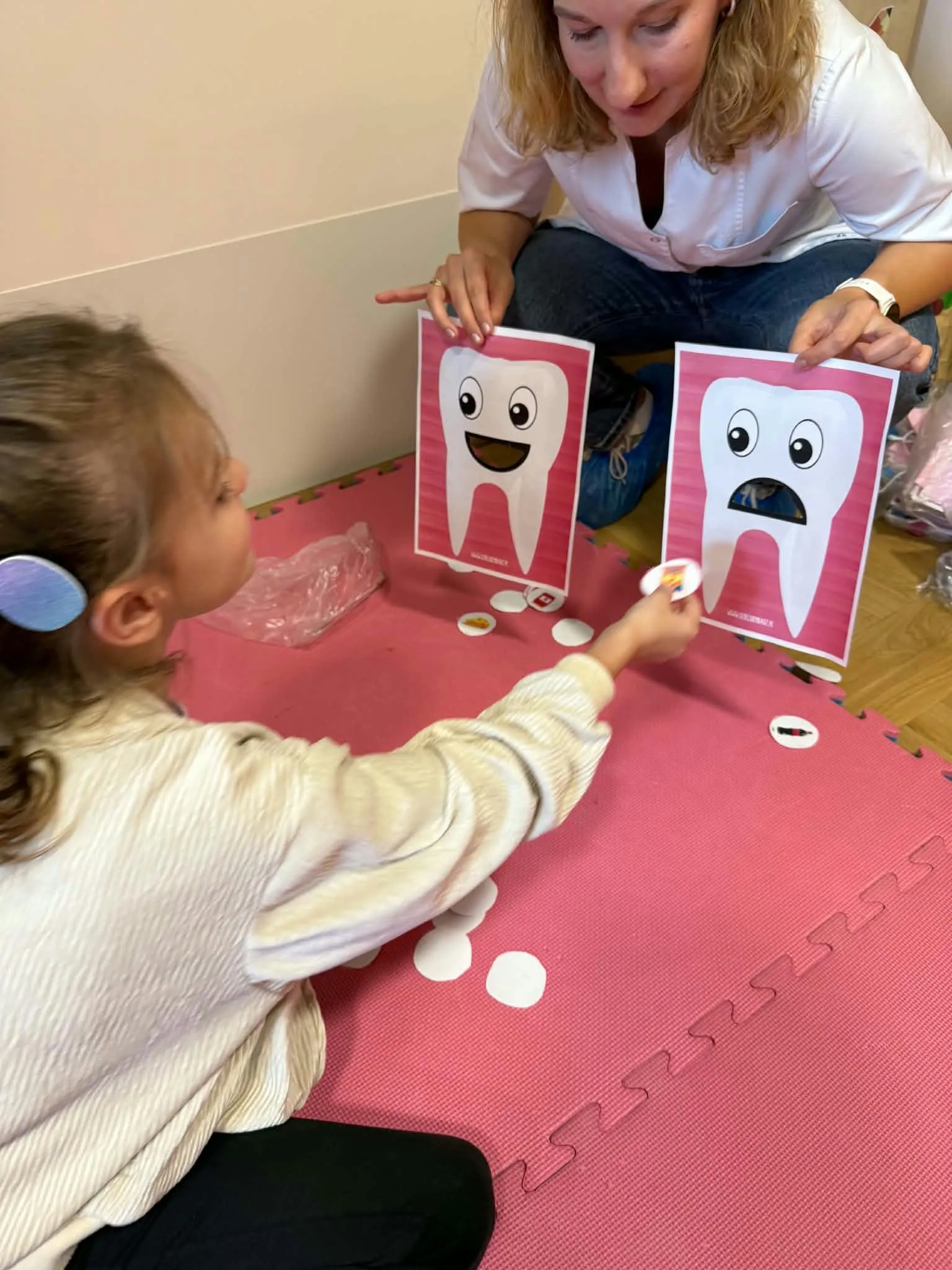 Uczennica podczas zabawy edukacyjnej dopasowuje obrazek produktu do ilustracji zdrowego lub chorego zęba.
