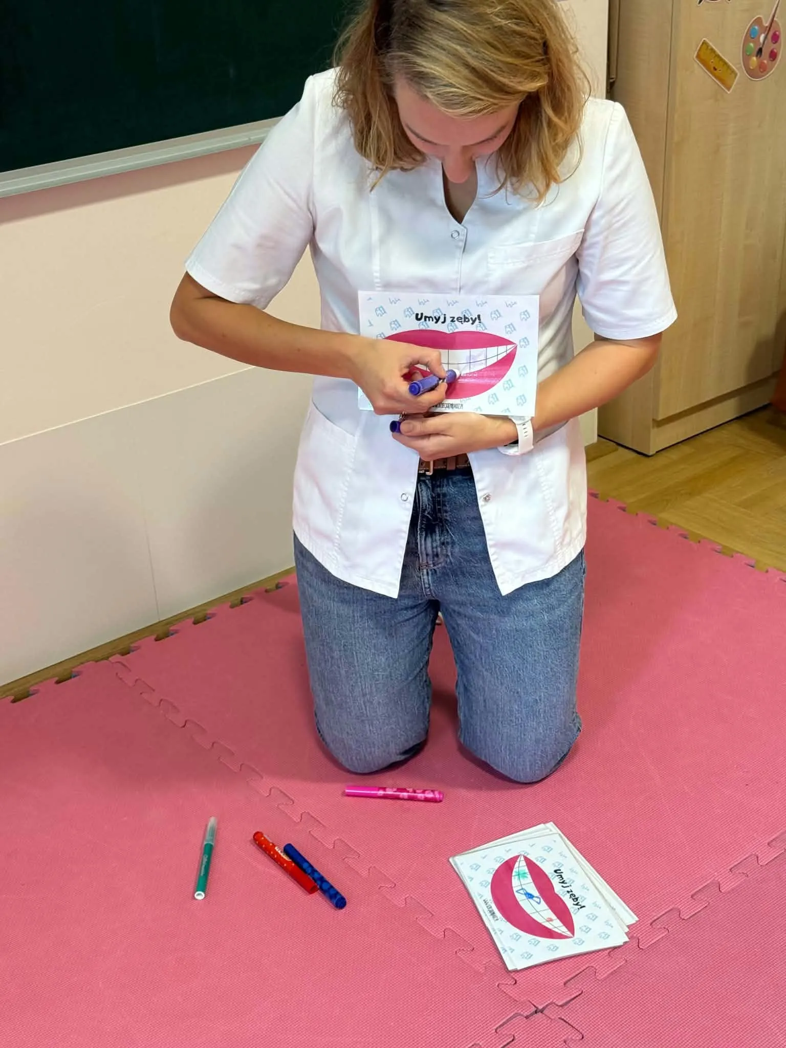 Higienistka stomatologiczna pokazuje dzieciom na ilustracji, jak dokładnie i prawidłowo szczotkować zęby.